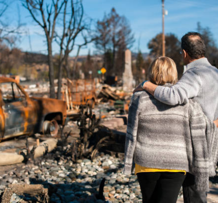 Couple standing in front of their burned down home