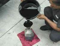 Mechanic pouring motor oil into container