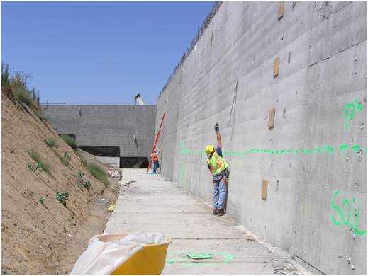 Construction workers completing work on concrete wall.