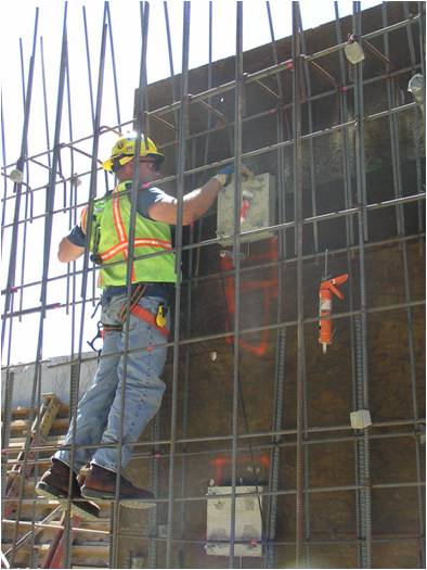 Construction worker working on pressure cell in rebar cage retaining wall
