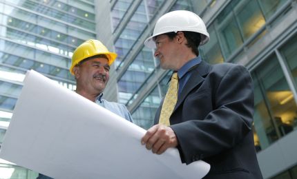 Two men in hard hats looking at blueprints