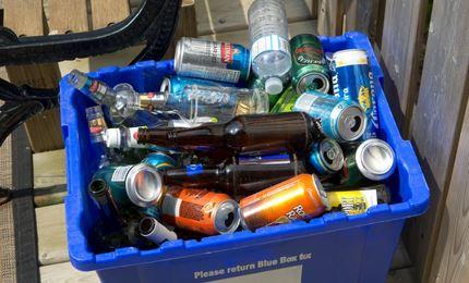 Blue recycling bin full of glass and plastic bottles, cans