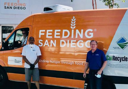Two men stand in front of a food recovery van with the Feeding San Diego logo on it