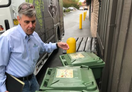 Local enforcement inspector looking at green organics curbside collection containers.