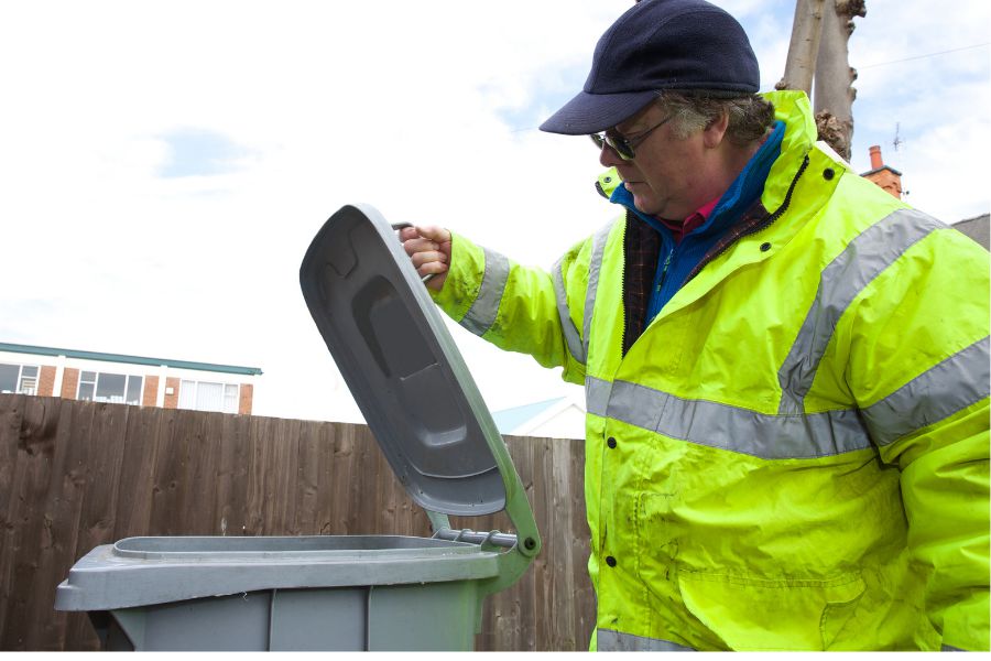 Inspector flipping a curbside container lid to inspect contents for contamination