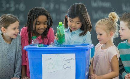 5 kids around a blue bottle recycling bin