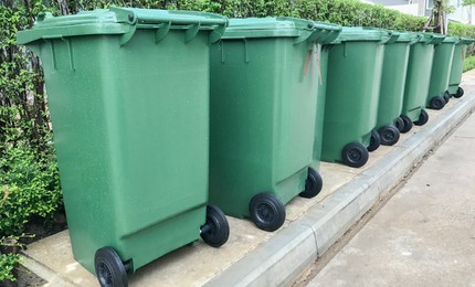 Row of several green recycling bins on wheels