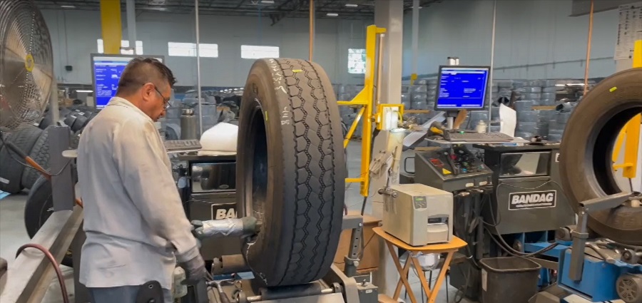 Man standing in front of a tire retreading machine