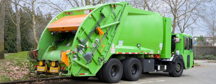 Garbage truck pouring trash into truck