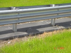 Weed abatement rubber mats near road guardrail