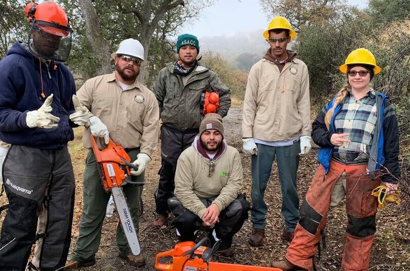 local conservation corps people outside with tools in front of trees