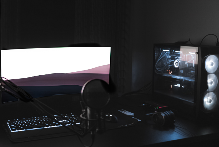 gaming computer with two monitors on desk in dark room.