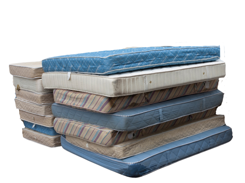 The image features a variety of used mattresses, each with distinct designs and colors, stacked on top of one another, showcasing their wear and diverse origins.